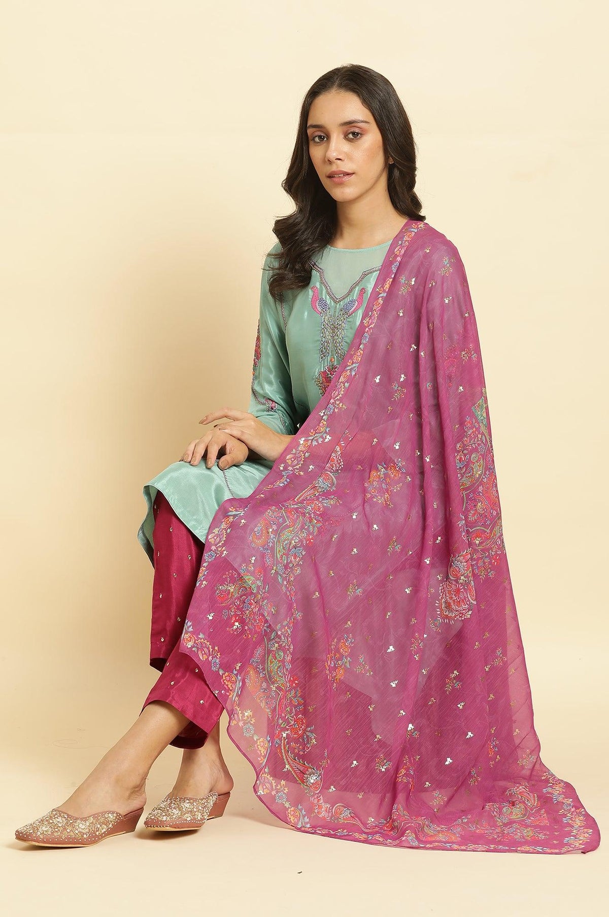 Woman wearing a modern kurta set with a pink dupatta and embellished footwear